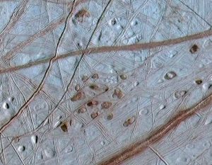 La surface d'Europe photographiée par Galileo montrant l'entrelacement des lignes et la présence de taches sombres appelées lenticules