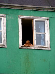Bébé inuit regardant par la fenêtre d'une maison